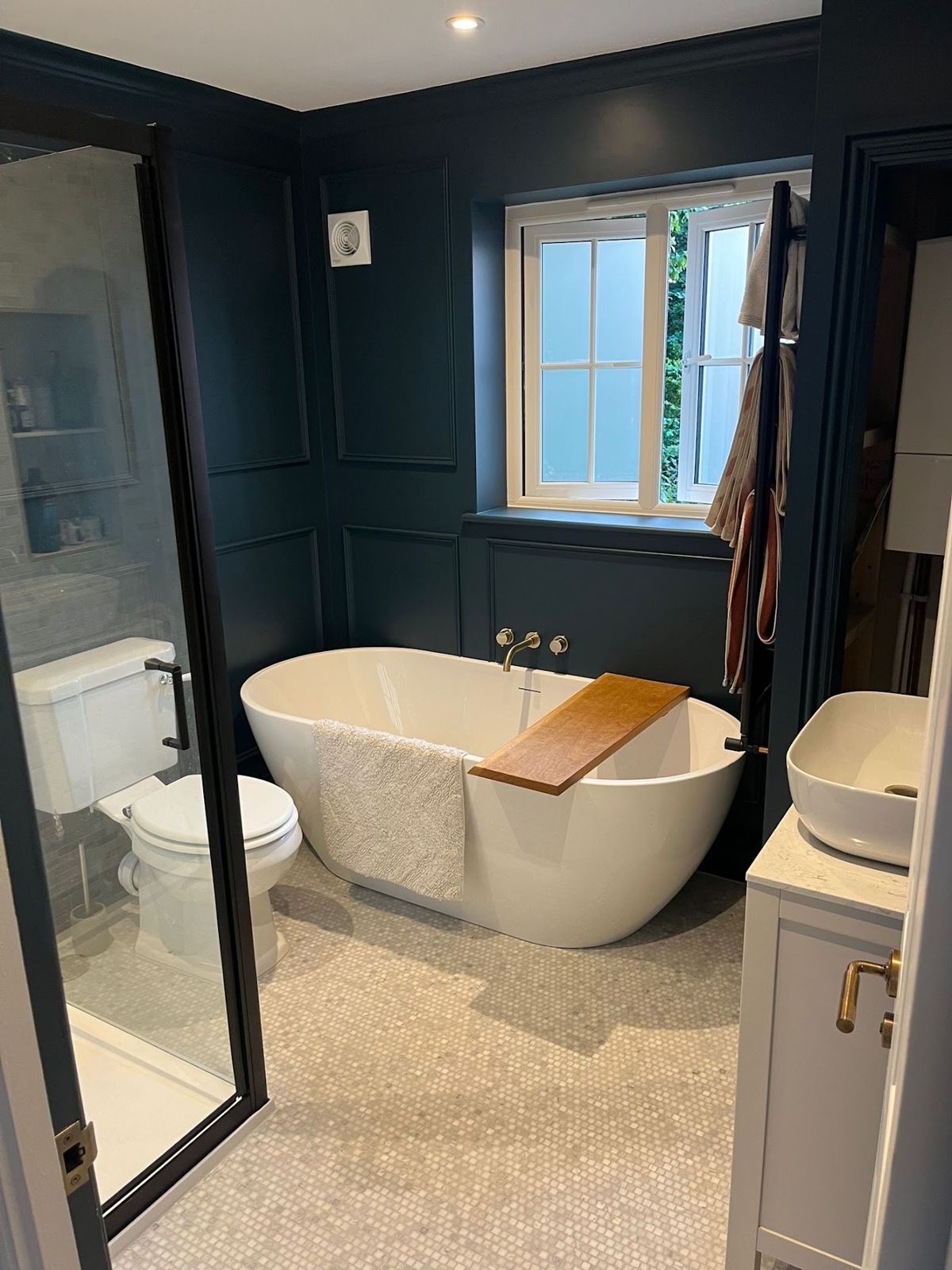 Dark blue panelled bathroom with a freestanding bath and walk-in shower