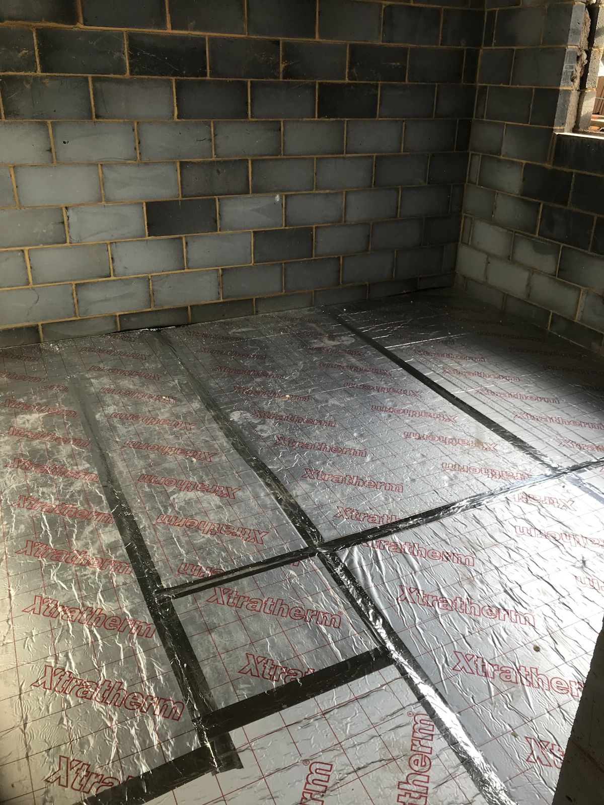 Foil-faced insulation boards laid across a floor ready for underfloor heating pipes