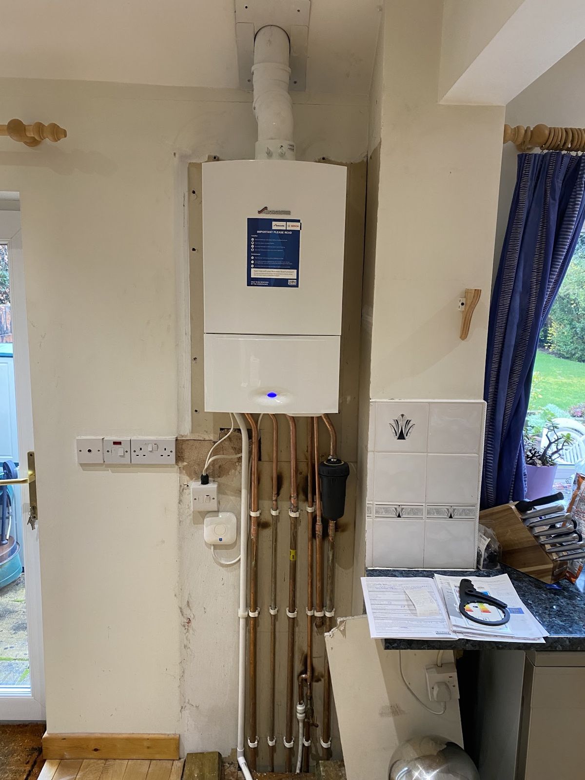 Worcester Bosch boiler installed on a kitchen wall with copper pipework below